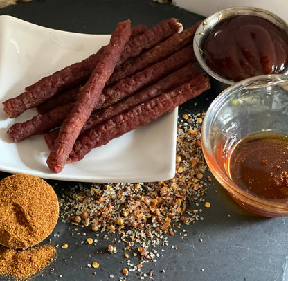 Plate displaying Honey BBQ Beef Jerky Sticks with bbq sauce and honey
